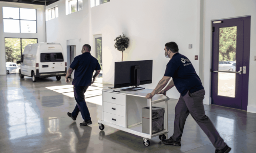 Landscape image of commercial office workers clearing out desks and furniture in a Kanata office setting, featuring muted industrial tones.